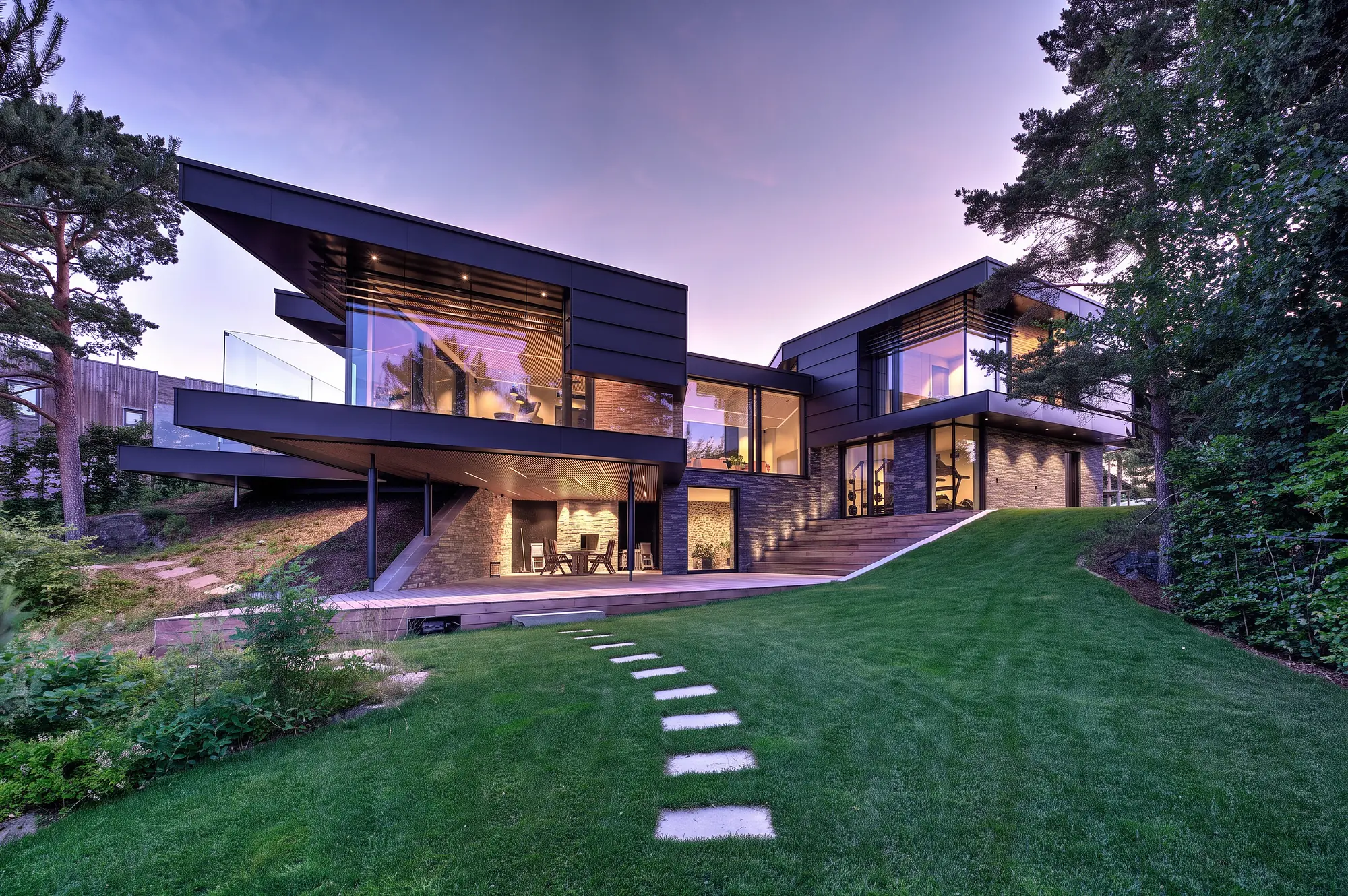 Modern hillside home with a cantilevered glass wing illuminated at dusk